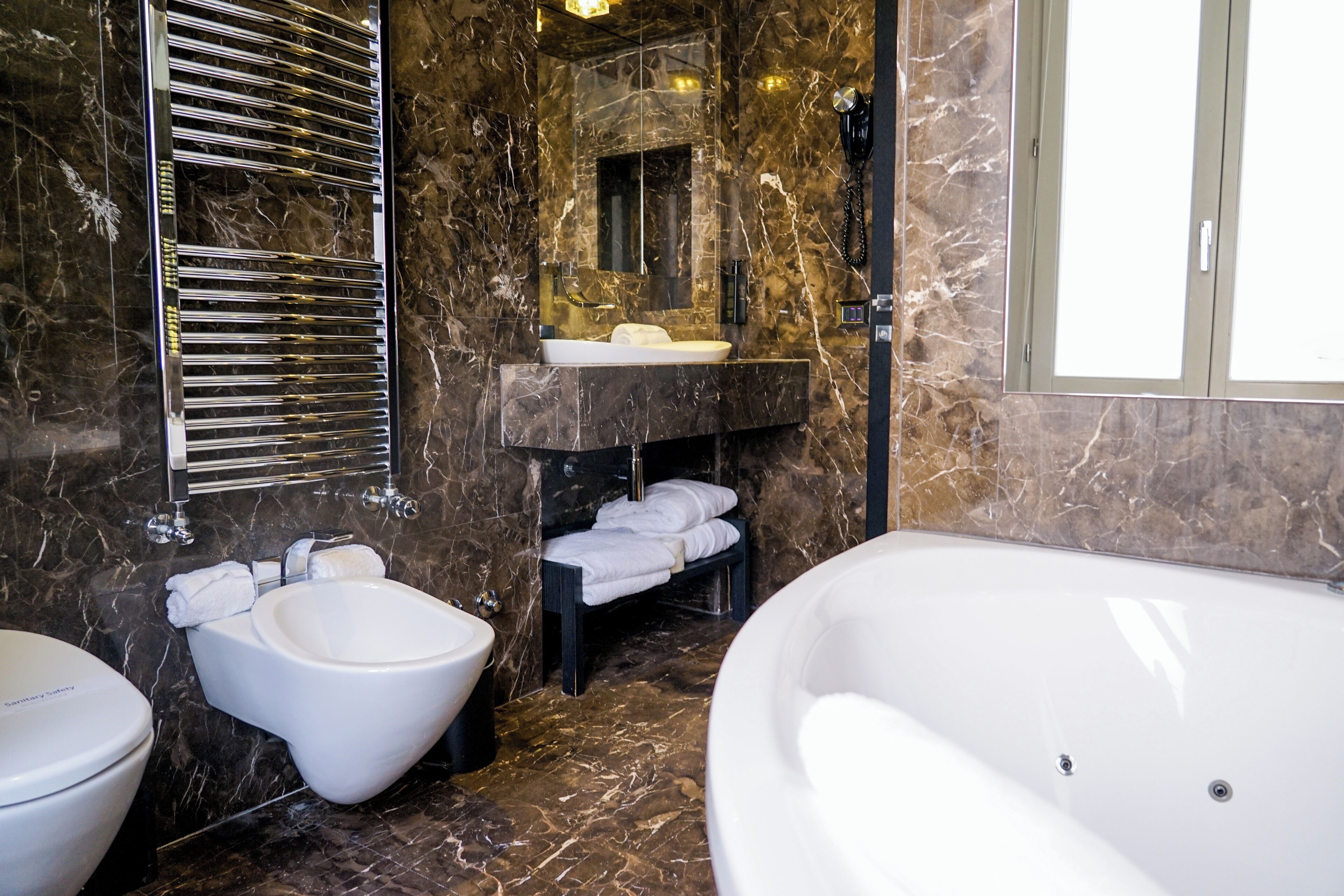 A modern bathroom with a bidet, a large bathtub, and a vanity with a mirror.