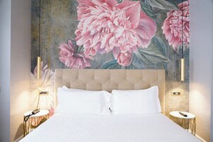 Een slaapkamer met een groot bed, een hoofdeinde, twee nachtkastjes en een bloemenmotief op de muur.