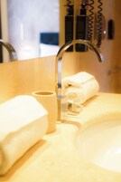 Een badkamer met een wastafel, een handdoek en een beker.