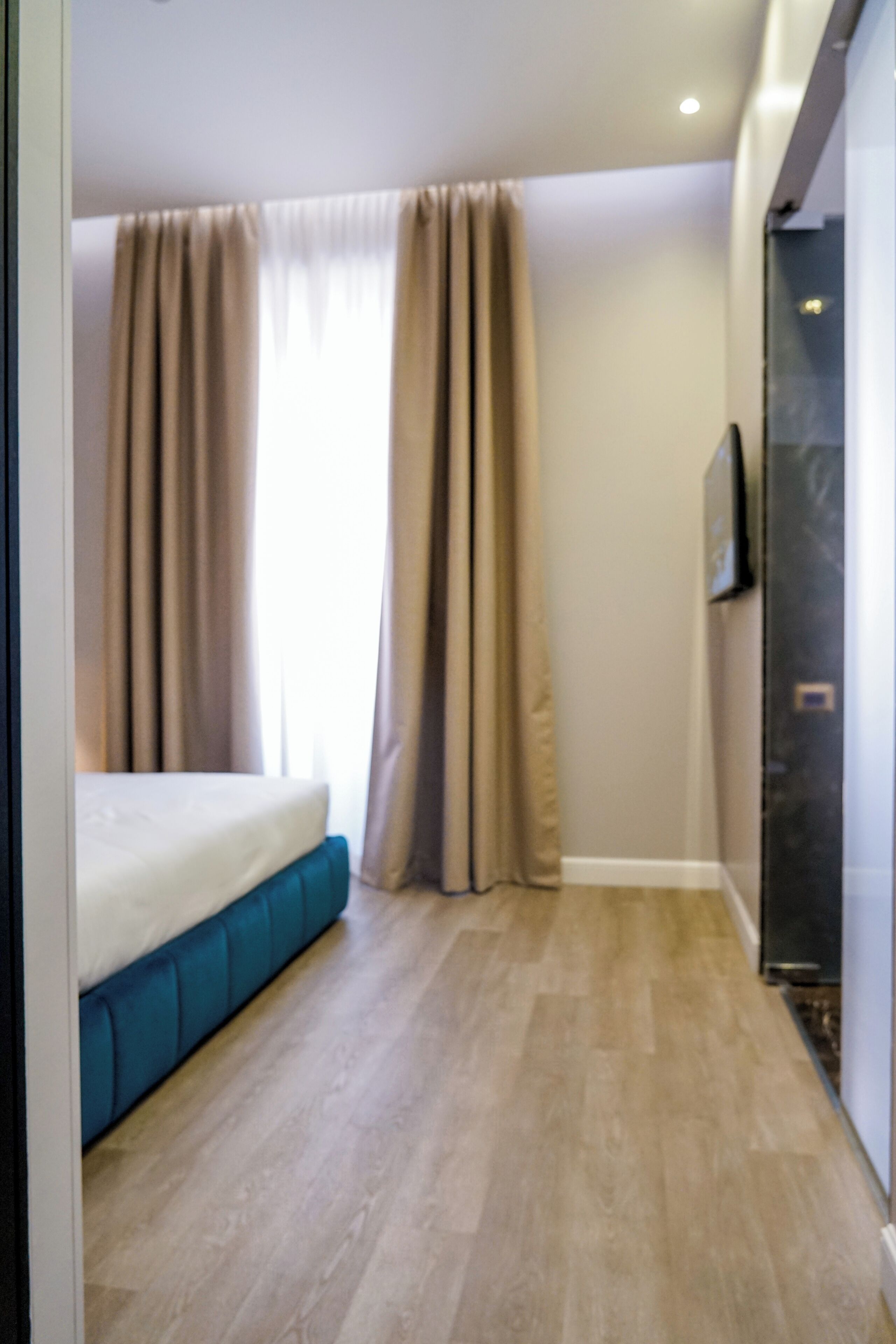 Une chambre à coucher avec un lit, des rideaux et un téléviseur.