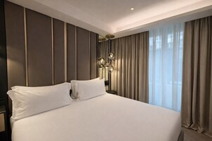 Een hotelkamer met een groot bed, een bedlampje en uitzicht op het omliggende landschap.