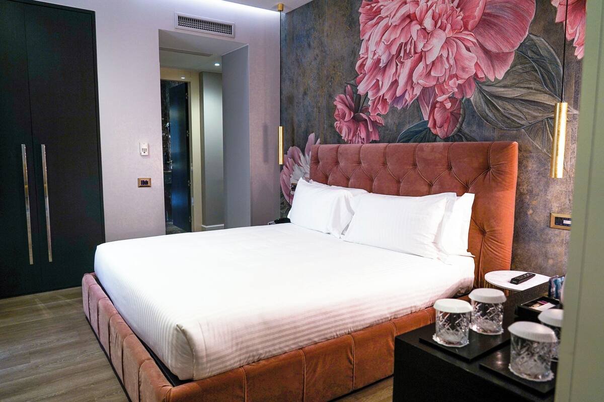 A neatly made bed with white linens, a tufted headboard, and bedside tables with decorative items.