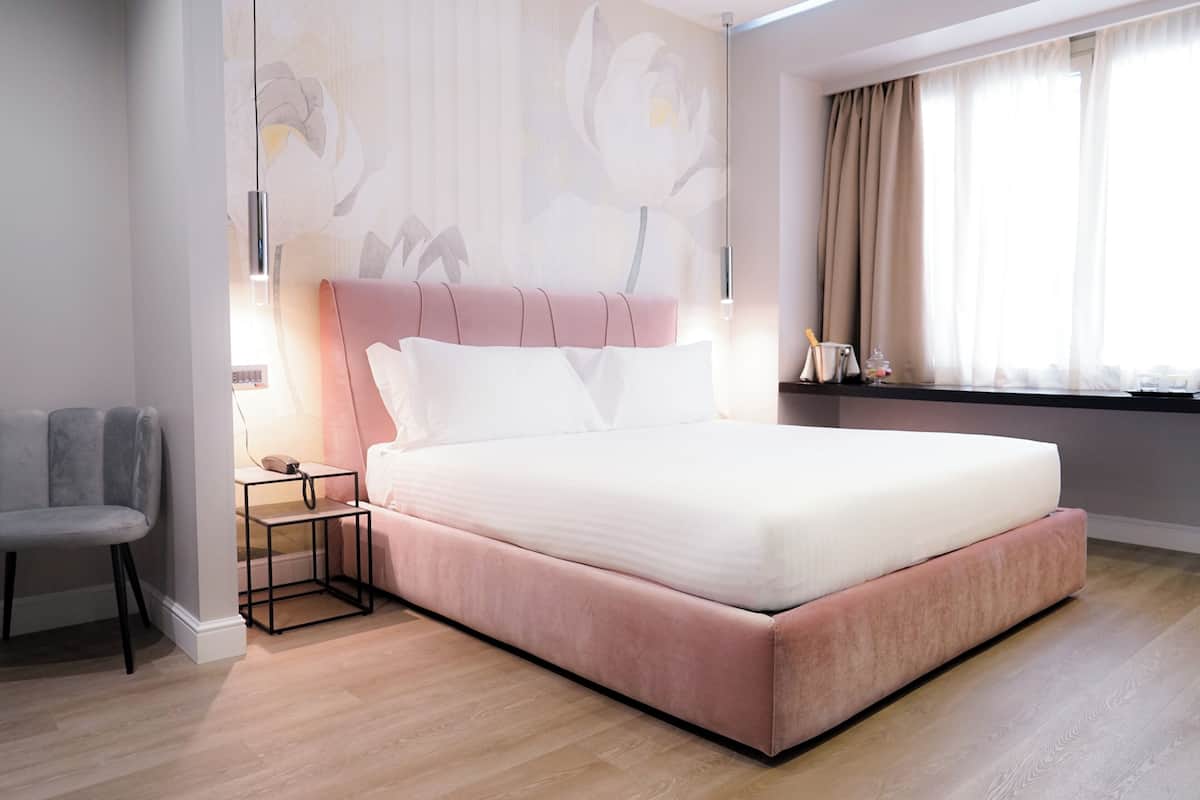 A modern bedroom with a large bed, a bedside table, a chair, and a wall with a floral mural.