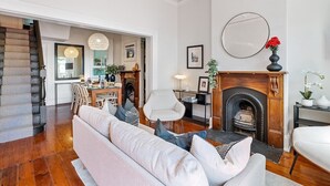 Una sala de estar con sofá, sillas, chimenea y comedor.