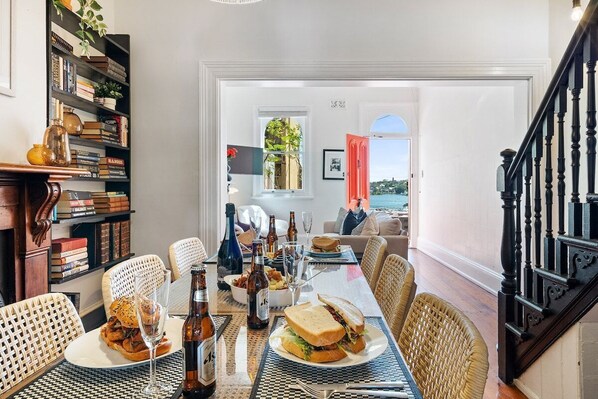 A dining area with a table set for two, a bookshelf, and a view of the outdoors.