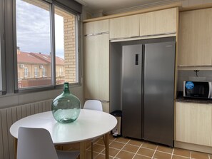 A modern kitchen with a stainless steel refrigerator, a microwave, and a round table with chairs.
