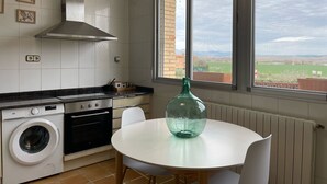 Una cocina con lavadora, horno y un amplio ventanal con vistas a un paisaje verde.