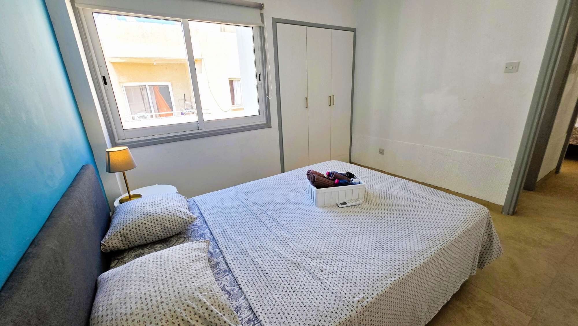 Une chambre à coucher avec un lit, une table de chevet avec une lampe, une fenêtre et une armoire.