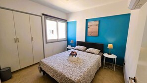 Une chambre à coucher avec un lit, une fenêtre, un tableau et une table de chevet.