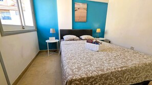 Een slaapkamer met een bed, twee nachtkastjes, een wanddecoratie en een raam.