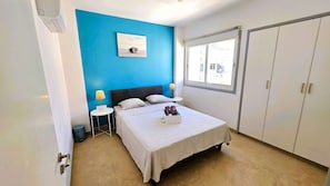Ein Schlafzimmer mit Bett, Nachttischen, einem Fenster und einem Kleiderschrank.