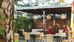 Une terrasse extérieure avec des meubles en osier et des lanternes suspendues.
