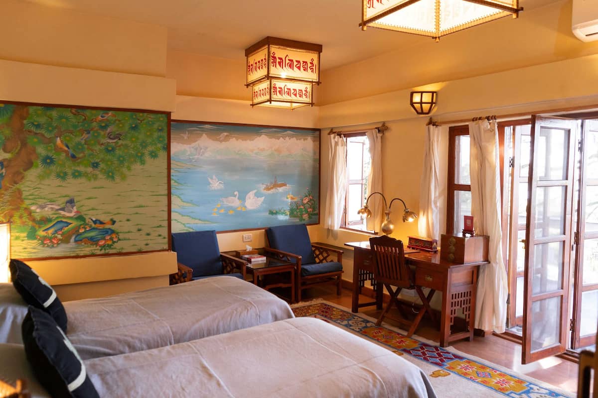 A room with two beds, a desk, a chair, and a large painting on the wall.