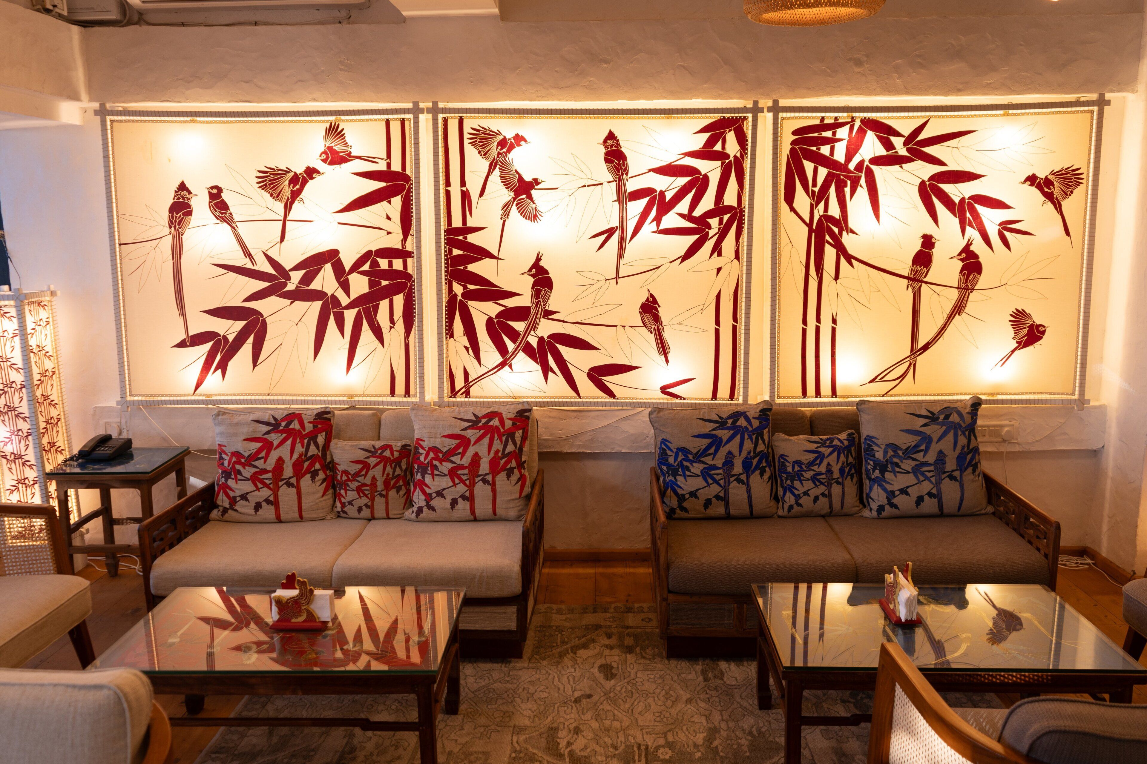 A living room with two sofas, a coffee table, and a decorative wall panel with bamboo and birds.
