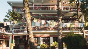 Un immeuble à plusieurs étages doté de balcons, de plantes en pot et d’un drapeau.