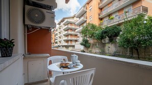 Ein Balkon mit Tisch für Zwei, einem weißen Stuhl und einem Deckenventilator.