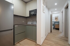 A modern kitchen with a built-in microwave, a sink, and a stainless steel refrigerator.