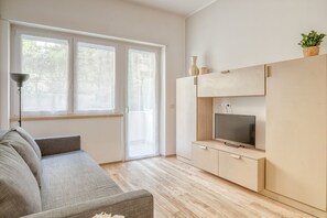 Een moderne woonkamer met een bank, televisie en houten vloer.