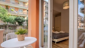 Ein Balkon mit Tisch und Stühlen, einem Blumentopf und Blick auf ein Gebäude mit Balkonen.