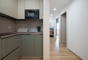 Una cocina moderna con microondas, pileta y alacenas.