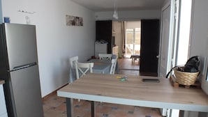 Une cuisine compacte comprenant un réfrigérateur, une table à manger avec des chaises et un petit tabouret.
