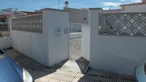 Un lotissement résidentiel fermé, délimité par un mur blanc, une porte en métal et un toit recouvert de tuiles.