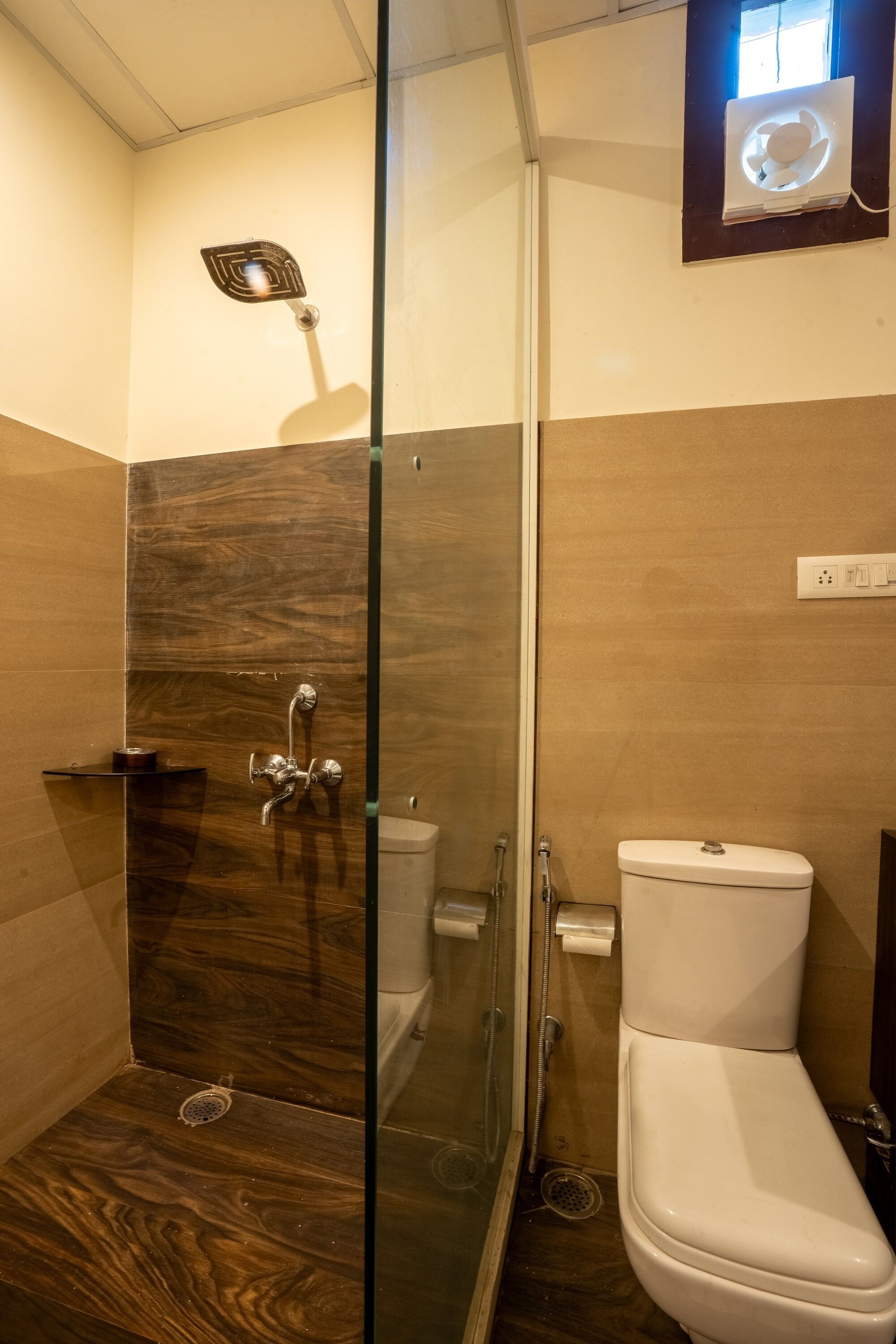 A bathroom with a glass-enclosed shower, a white toilet, and a wooden vanity.