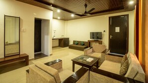 Una sala de estar moderna con sofá, sillones, una mesa de centro, televisor y ventilador de techo.