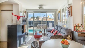 A modern living room with a pool view, a sofa, a dining table, and a TV. - Lovely home in Cartagena with kitchen (Cartagena)