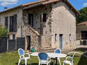 A rustic stone house with a covered porch, a small staircase, and a table with chairs in the foreground. - Authentic Cottage near Confolens, Pets Allowed (Esse)