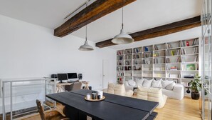 Un espacio habitable moderno con comedor, sofá, estantería y área de cocina.