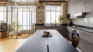 Una cocina moderna con una isla grande, electrodomésticos de acero inoxidable y ventanas amplias.