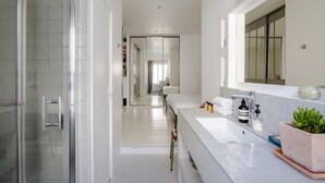 Un baño moderno con cabina de ducha de vidrio, un espejo grande y un lavamanos blanco con encimera.