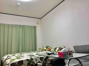 A room with a bed, a glass table, a grey sofa, and a green curtain. - Room 202 reserved 2 people Hino Room 2 Shinjuku  - Room 202 / Hino Tokyo (Hino)