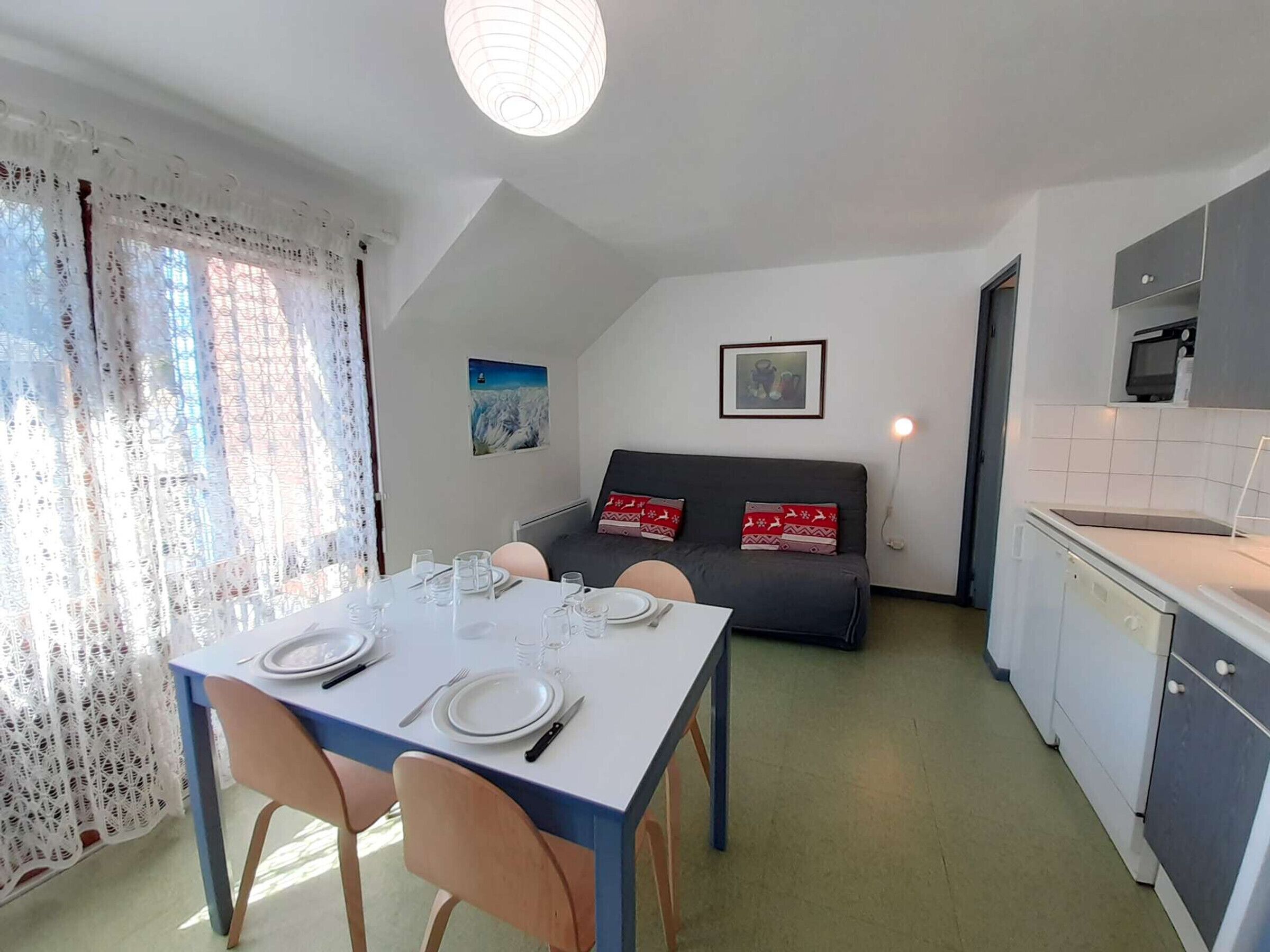 A compact living space with a dining area, kitchenette, and a sofa with decorative pillows.