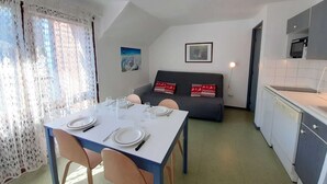 A compact living space with a dining area, kitchenette, and a sofa with decorative pillows. - Cozy studio for 4 with balcony, parking, and gym in St Lary Soulan (Saint-Lary-Soulan)
