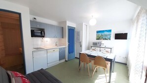 A compact kitchen with a microwave, sink, and dining area with chairs and a table. - Cozy studio for 4 with balcony, parking, and gym in St Lary Soulan (Saint-Lary-Soulan)