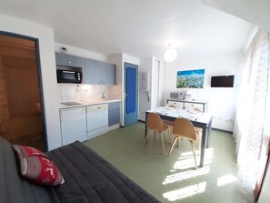 Une cuisine compacte équipée d’un four à micro-ondes, d’un évier et d’un coin repas avec des chaises et une table.