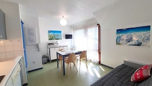 A compact living space with a kitchenette, dining area, and a bed. - Cozy studio for 4 with balcony, parking, and gym in St Lary Soulan (Saint-Lary-Soulan)