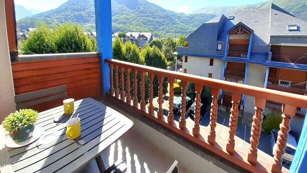 A balcony with a wooden table, two yellow cups, and a potted plant. - Cozy studio for 4 with balcony, parking, and gym in St Lary Soulan (Saint-Lary-Soulan)