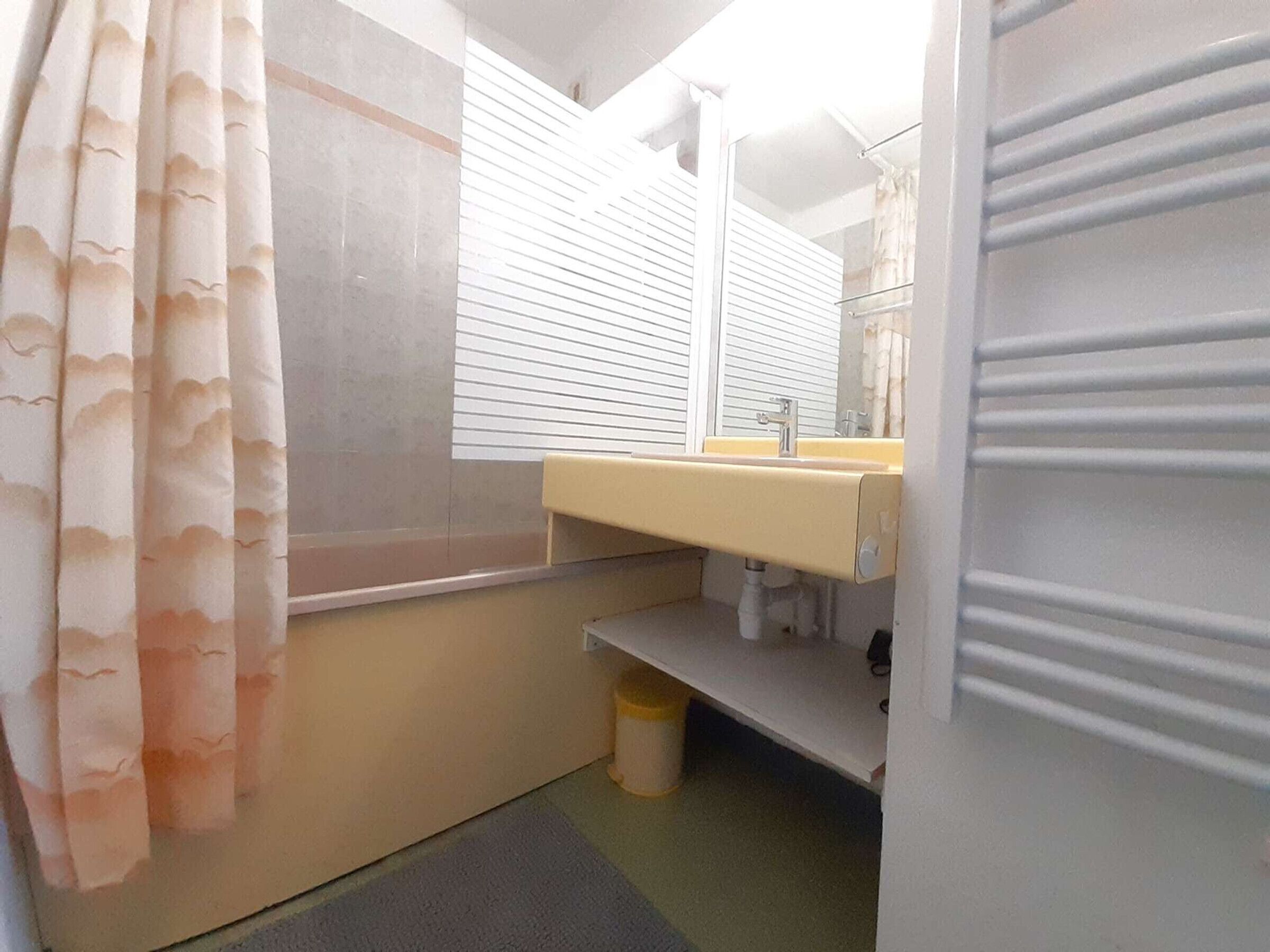 Un bagno con lavandino, specchio e tenda della doccia.