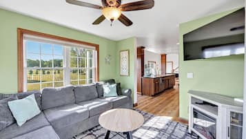 Un salon avec un canapé, une table basse ronde et un ventilateur de plafond.