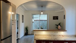 A modern kitchen with a marble countertop, stainless steel refrigerator, and red cabinets.