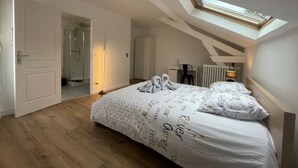 A bedroom with a skylight, a bed with towels, a desk, and a radiator.
