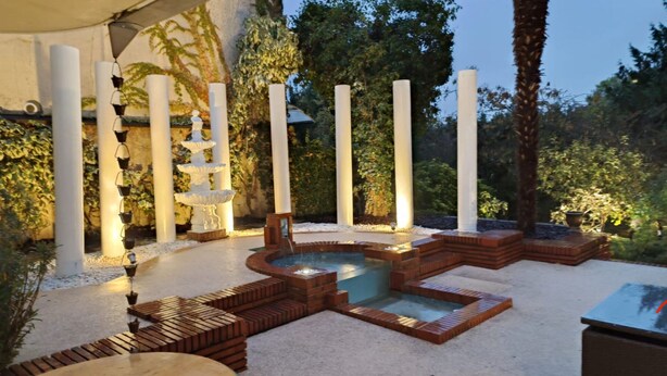A hot tub surrounded by brick seating and white pillars.