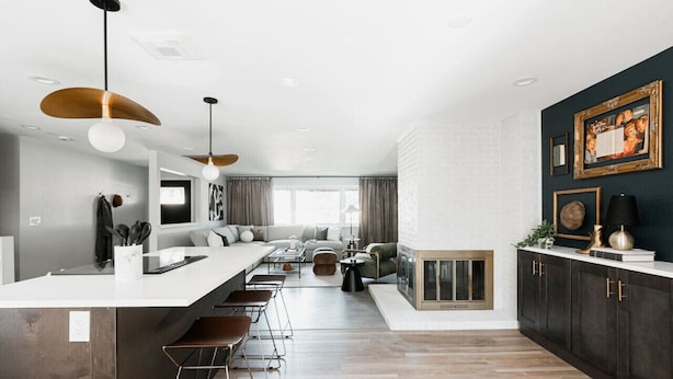 A modern kitchen with a central island, pendant lighting, and a dark-colored cabinet with gold handles. - Designer Home with HotTub, Movie Room, Firepit (Arvada)