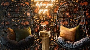 Two black wire chairs with cushions, a small table with a candle, and a wall with a rabbit pattern and a neon sign. - Designer Home with HotTub, Movie Room, Firepit (Arvada)