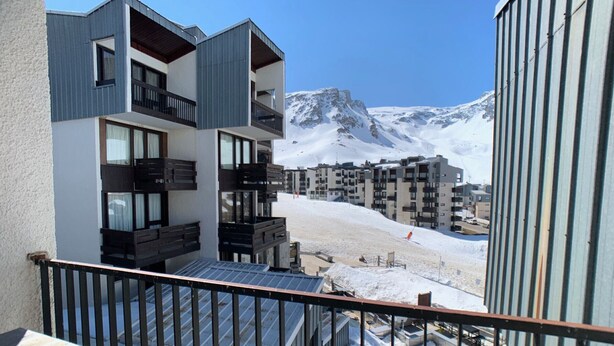 Ein modernes Gebäude mit Balkonen mit Blick auf eine verschneite Berglandschaft.
