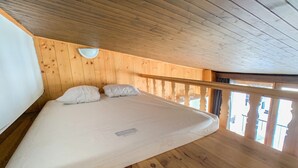 Ein Zimmer mit Holzboden, einem Bett und einem Balkon.