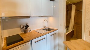 Eine kompakte Küche mit weißen Schränken, einer Holz Arbeitsplatte, einer Edelstahl-Spüle und einem eingebauten Herd.
